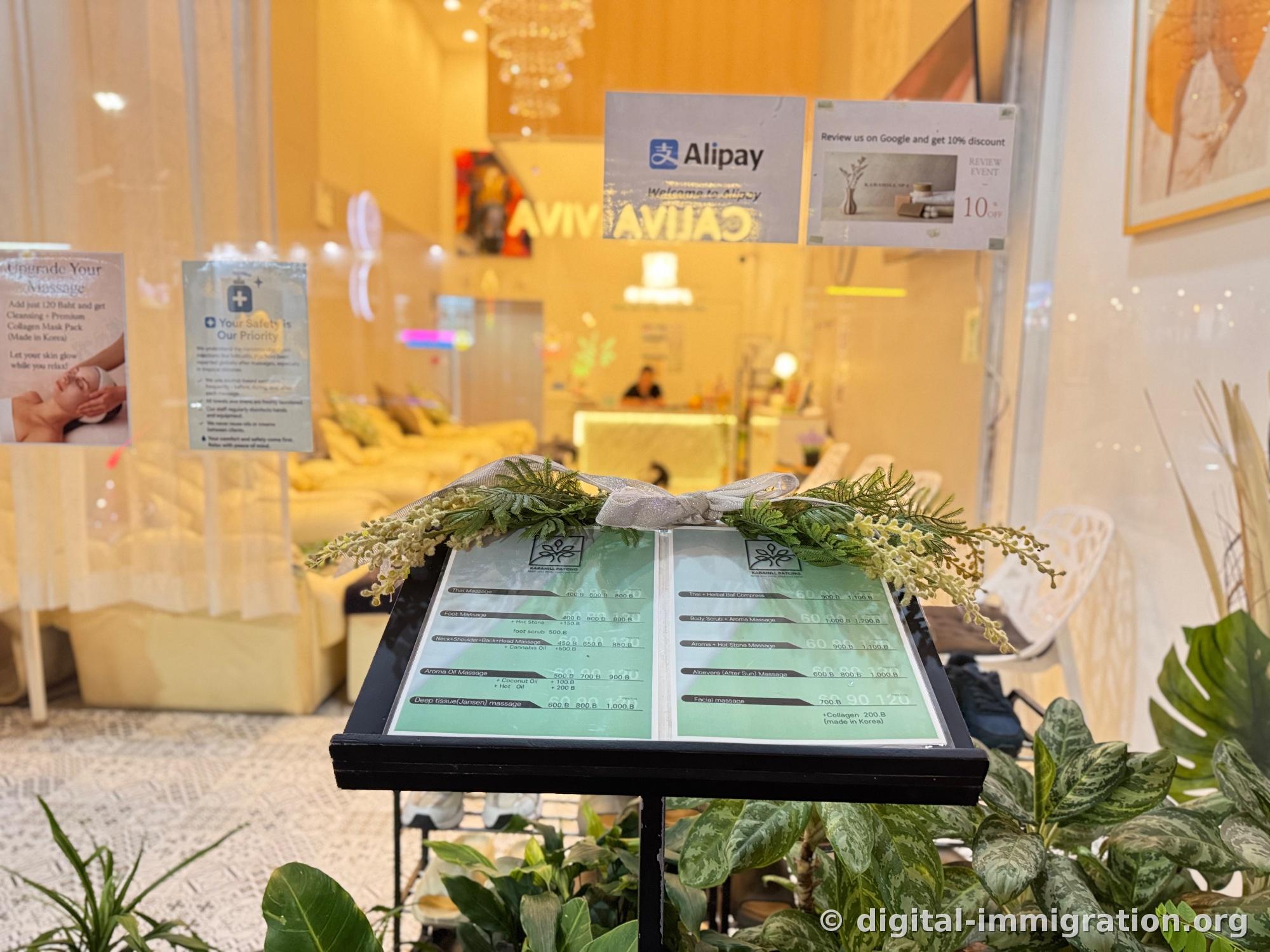 Green massage menu board displayed on a black stand in front of the shop, with Alipay payment sign and Google review 10% discount notice on the glass behind