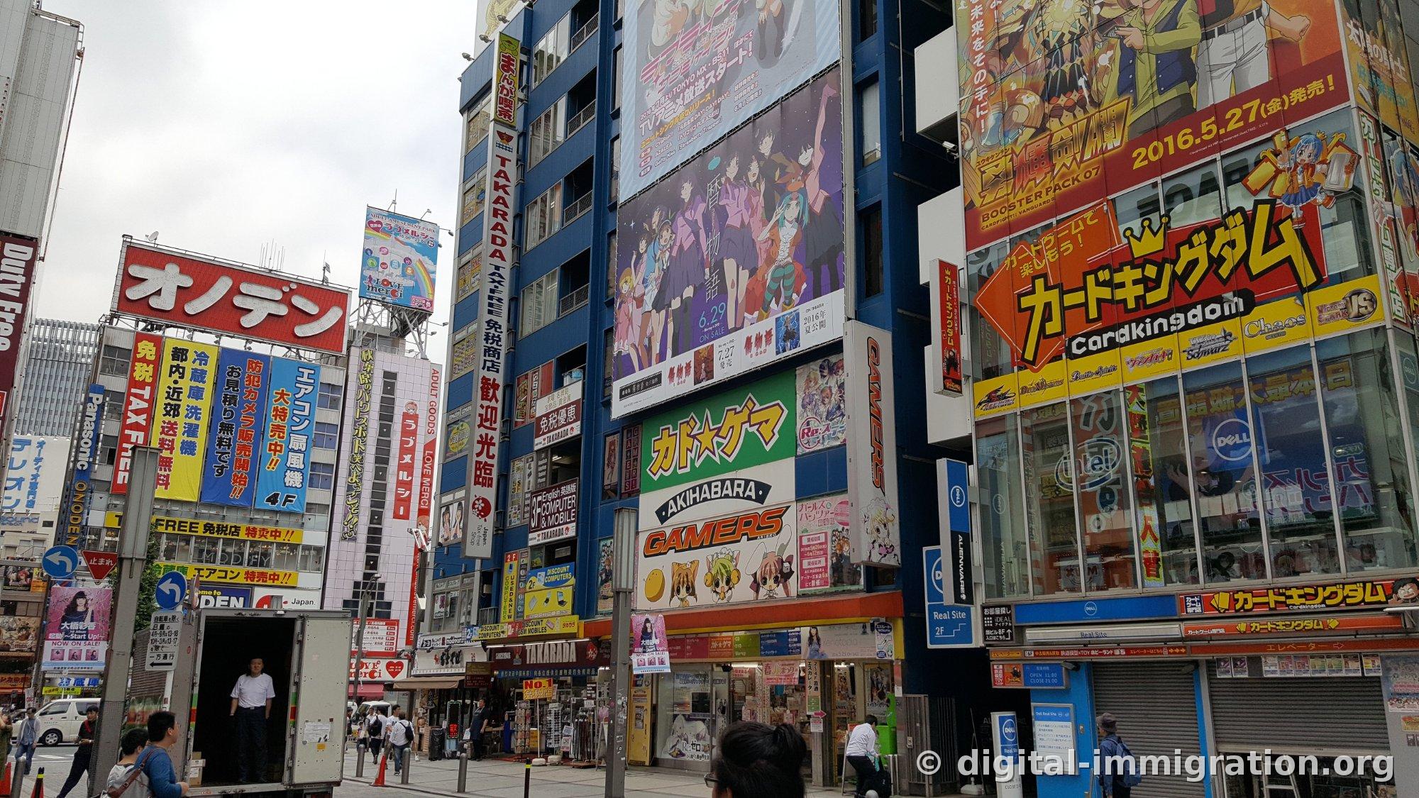 Chuo-dori buildings with densely overlapping signs for Onoden, Takarada duty-free, Gamers Akihabara, and Card Kingdom