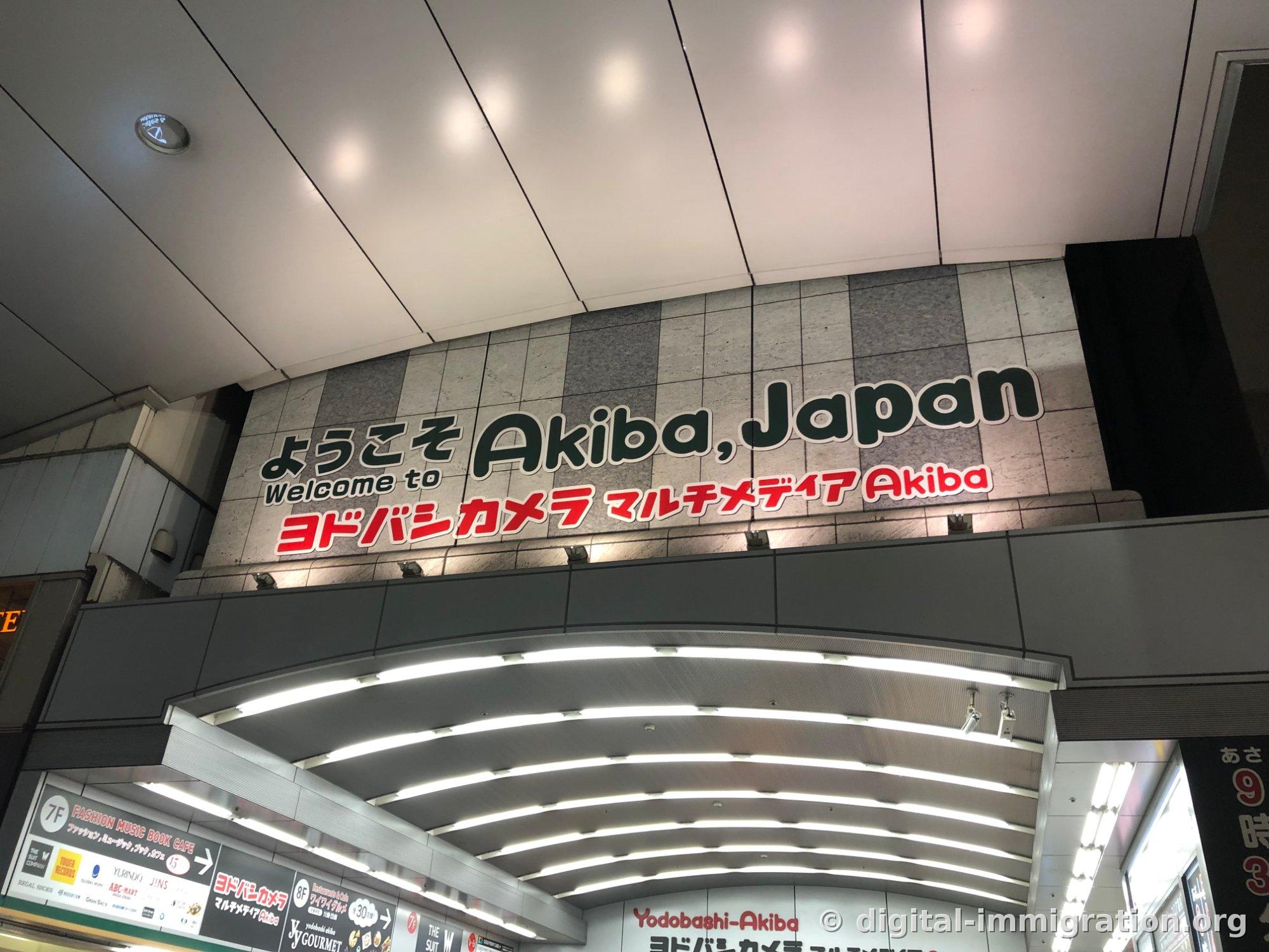 Building entrance ceiling with a sign reading 'Welcome to Akiba, Japan / Welcome to Yodobashi Camera Multimedia Akiba'