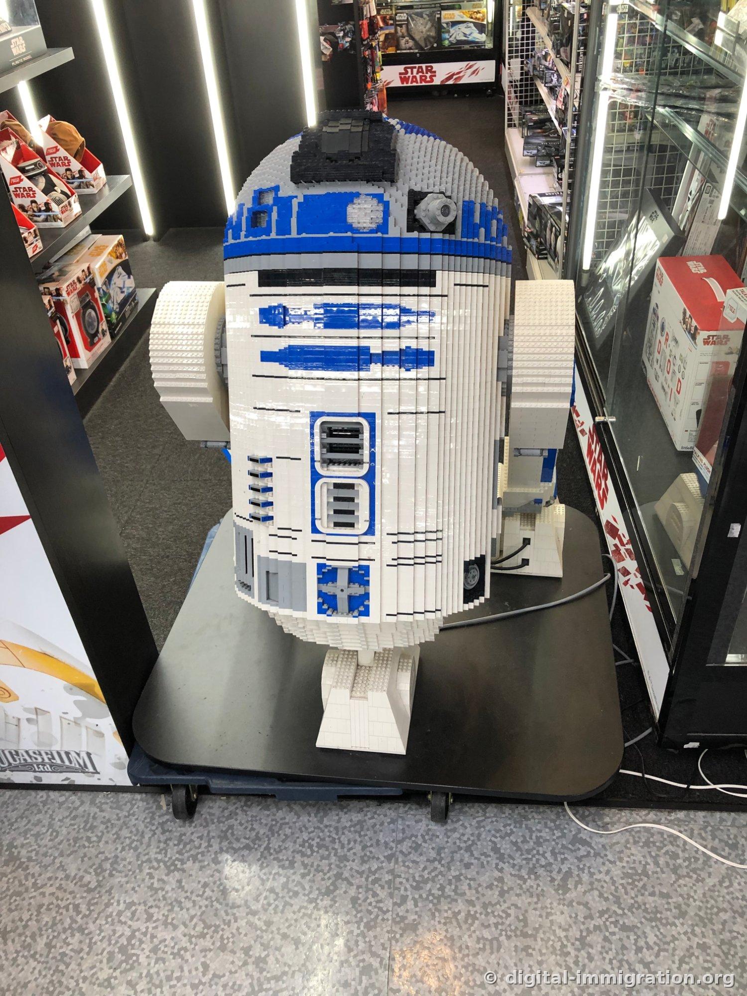 Life-sized R2-D2 made from Lego bricks displayed on the store's wheeled stand