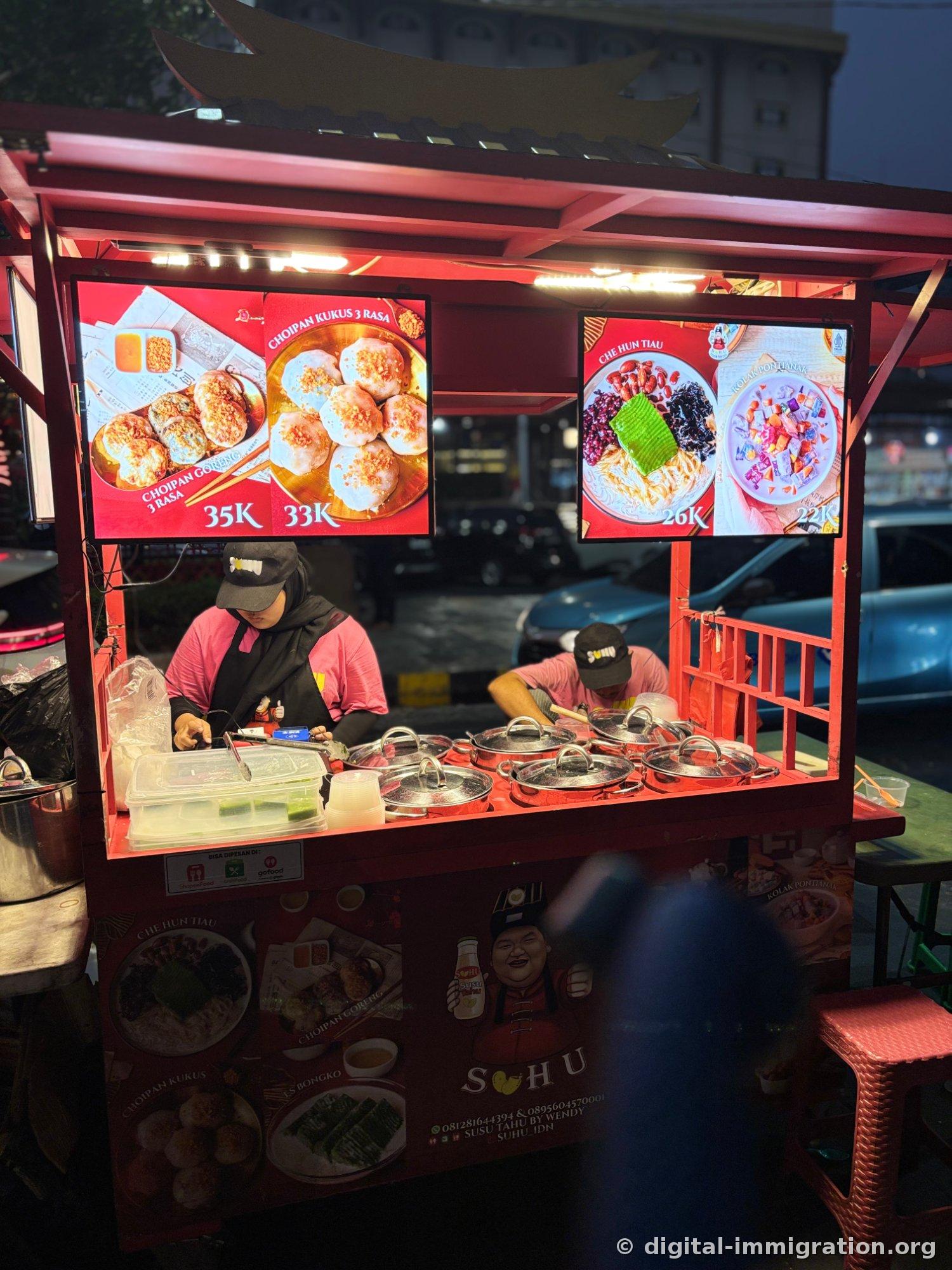 Red-roofed SUHU food cart with menu photo board showing Choi Pan Goreng 35K·Choi Pan Kukus 33K·Che Hun Tiau 26K·Kolak Pontianak 22K, and steamer lids lined up on the counter